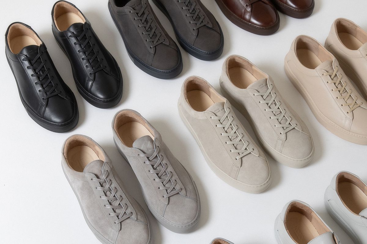 Koio Capri low-top sneakers in black, gray, brown, beige, and white lined up in a grid, arranged on a white background