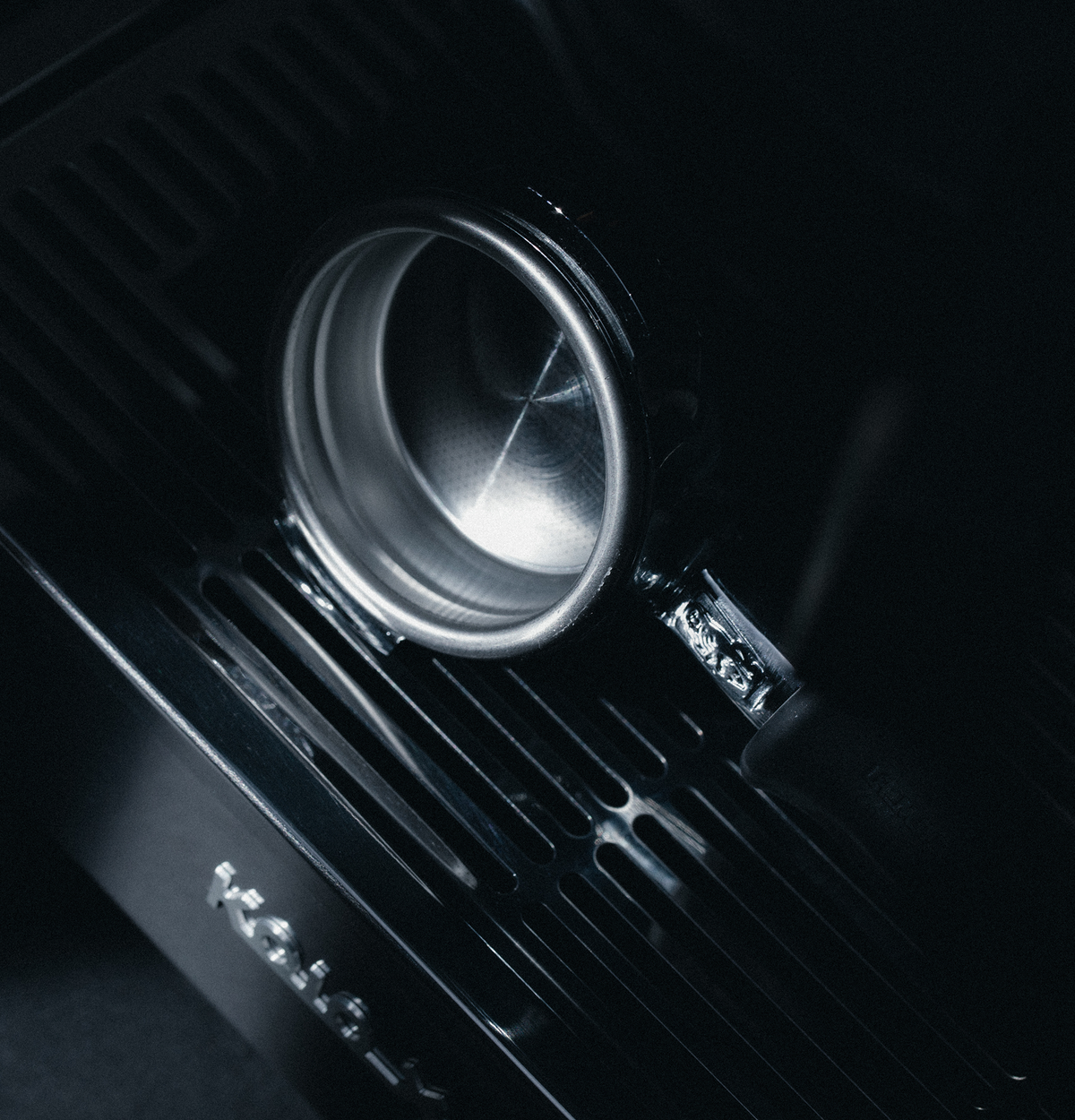 Close-up of a La Marzocco espresso machine showcasing its group head and portafilter with a dark background