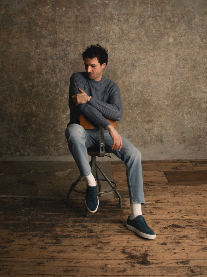 Man sitting on chair wearing men's Italian blue suede leather dress sneakers