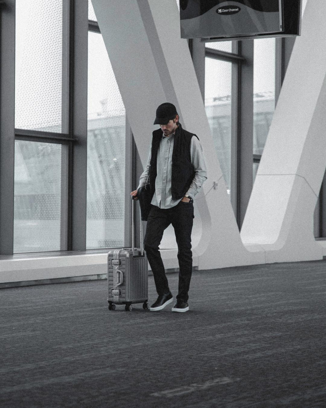 Man wearing black Capri leather low-top sneakers pulls a suitcase through an airport