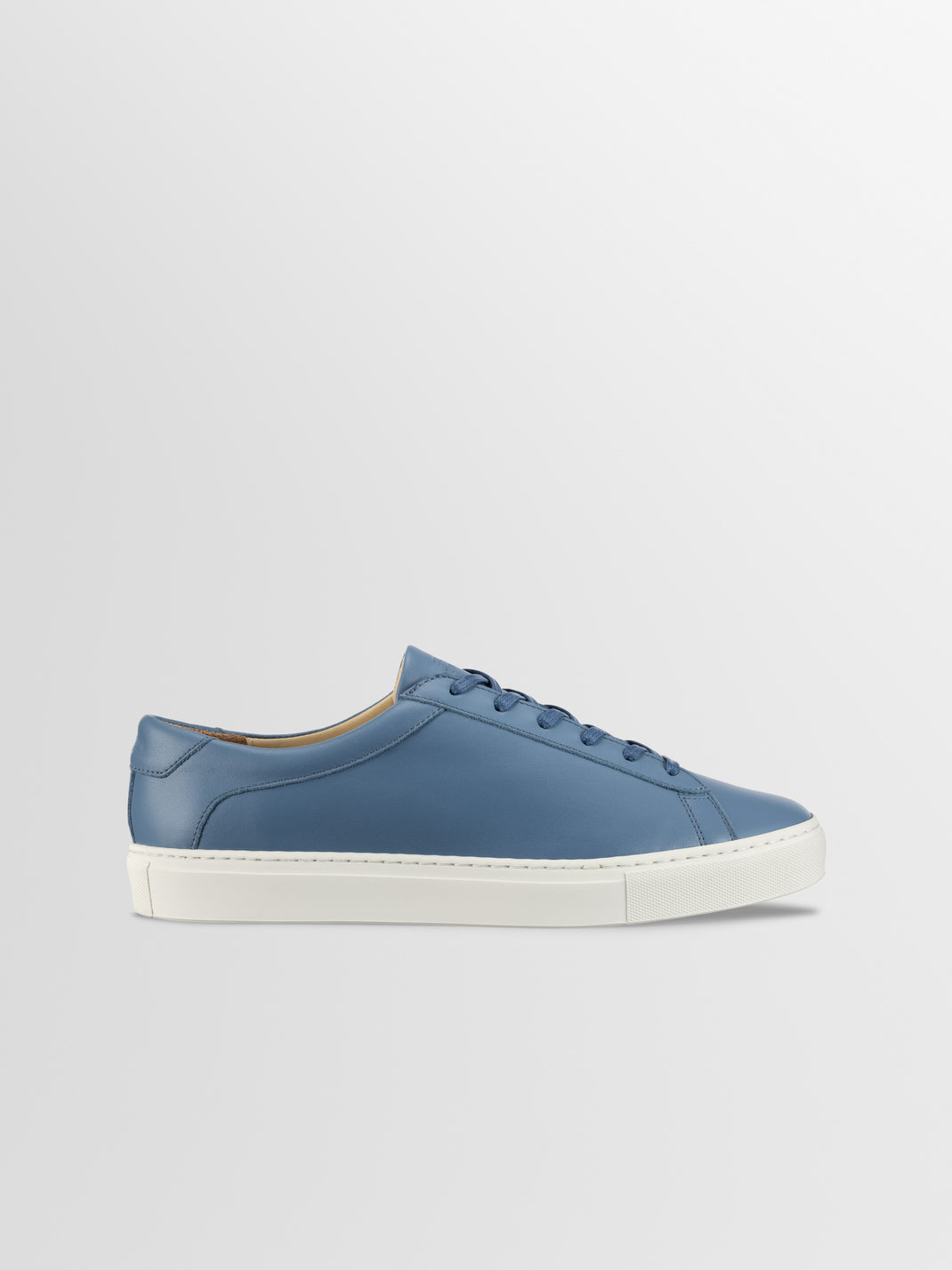 Side view of Capri in Bay blue leather low-top sneaker showcasing white rubber sole with a light gray background