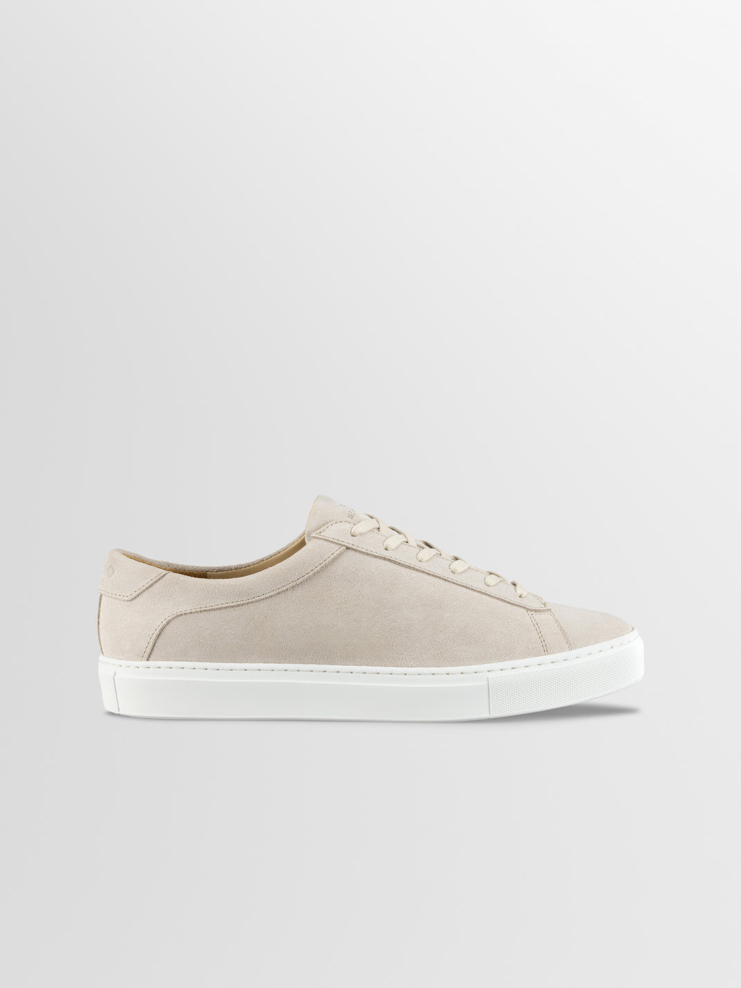 Side view of men’s Capri low-top sneaker in ivory suede showcasing white rubber sole and laces against a light gray background
