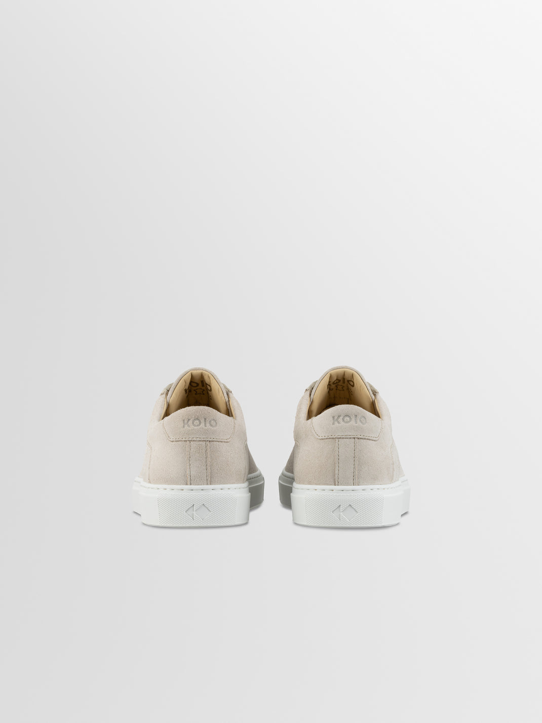 Rear view of Capri in Ivory low-top sneakers showcasing cream suede uppers and white rubber soles with a light gray background