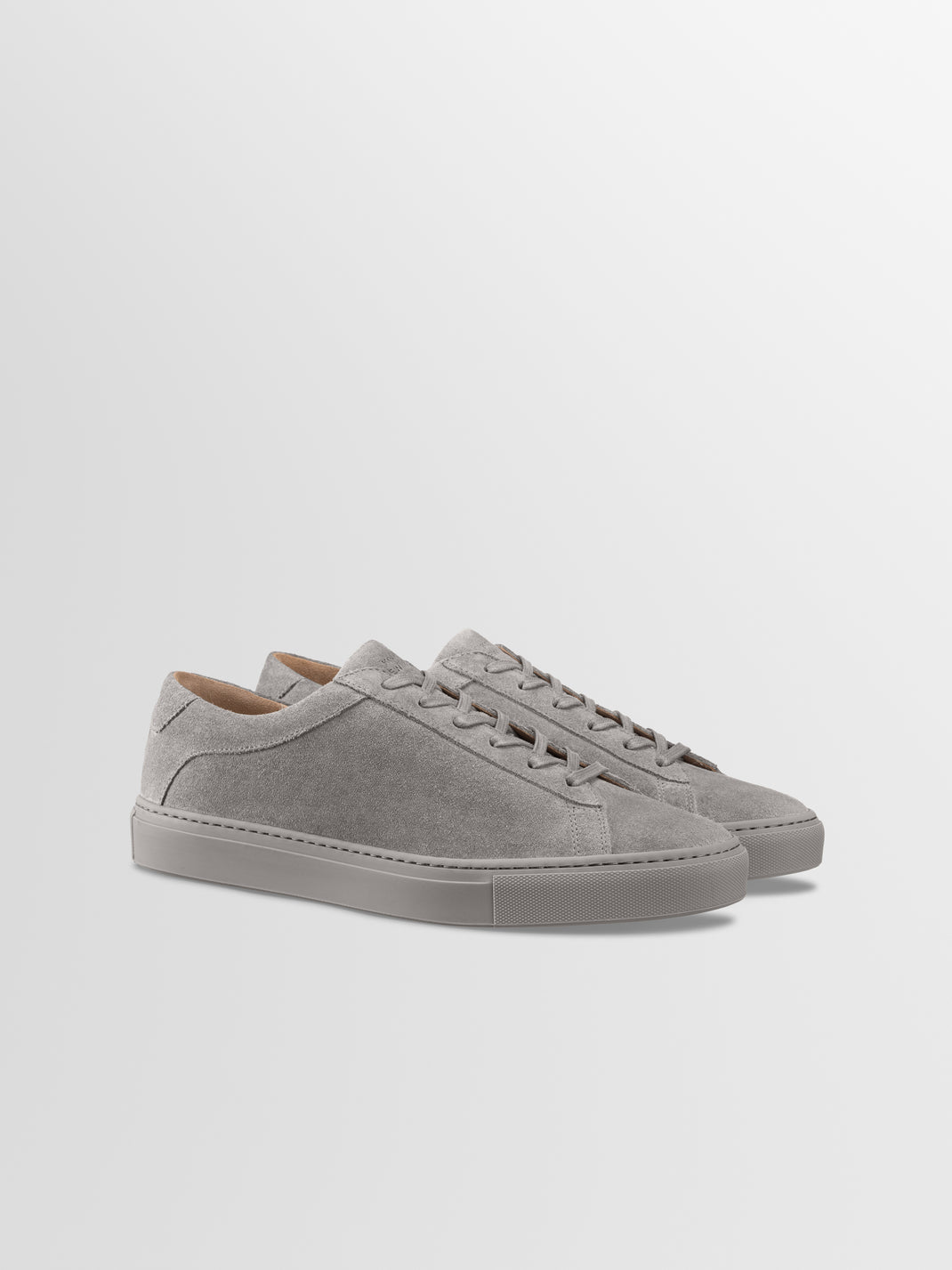 Front three-quarter view of men’s True Grey suede Capri low-top sneakers with matching rubber soles on a light gray background