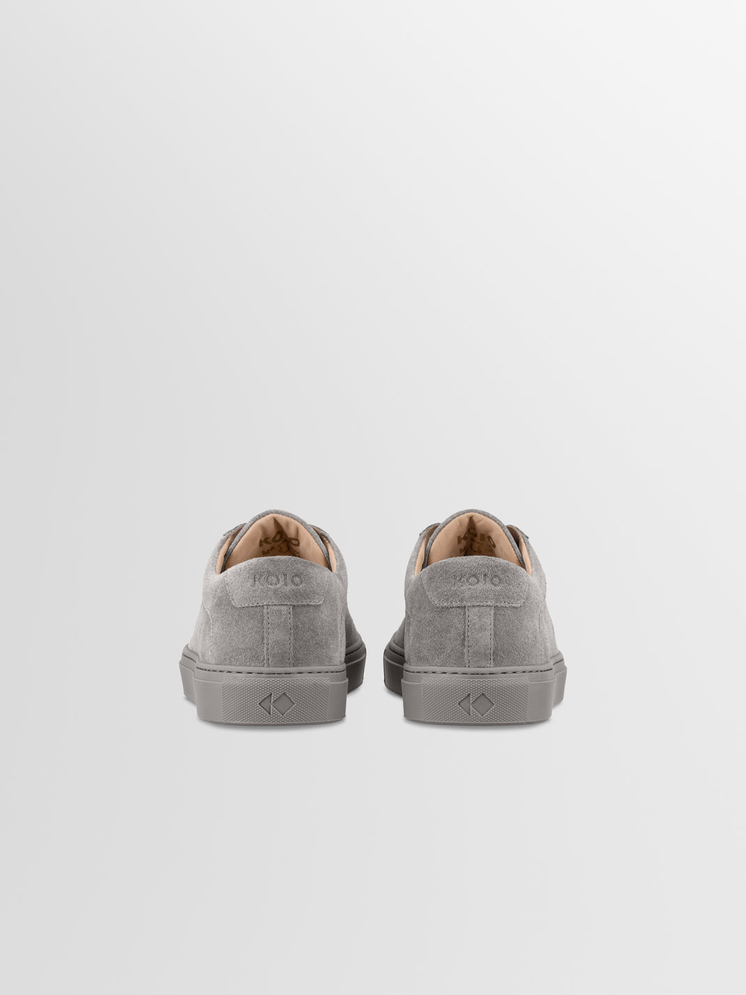 Rear view of men’s Capri low-top sneakers in mineral grey suede showcasing KOIO heel logos on a light grey background
