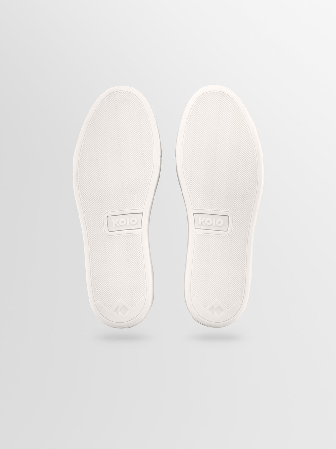 Bottom view of Capri low-top sneaker showcasing patterned rubber soles with a light gray background