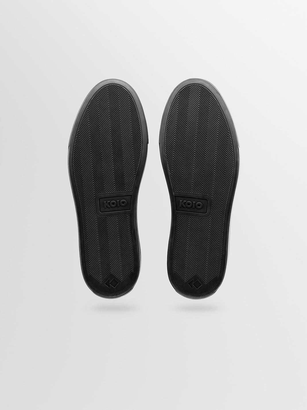 Underside view of Capri Nero low-top sneaker showcasing black rubber sole with herringbone tread on a light gray background