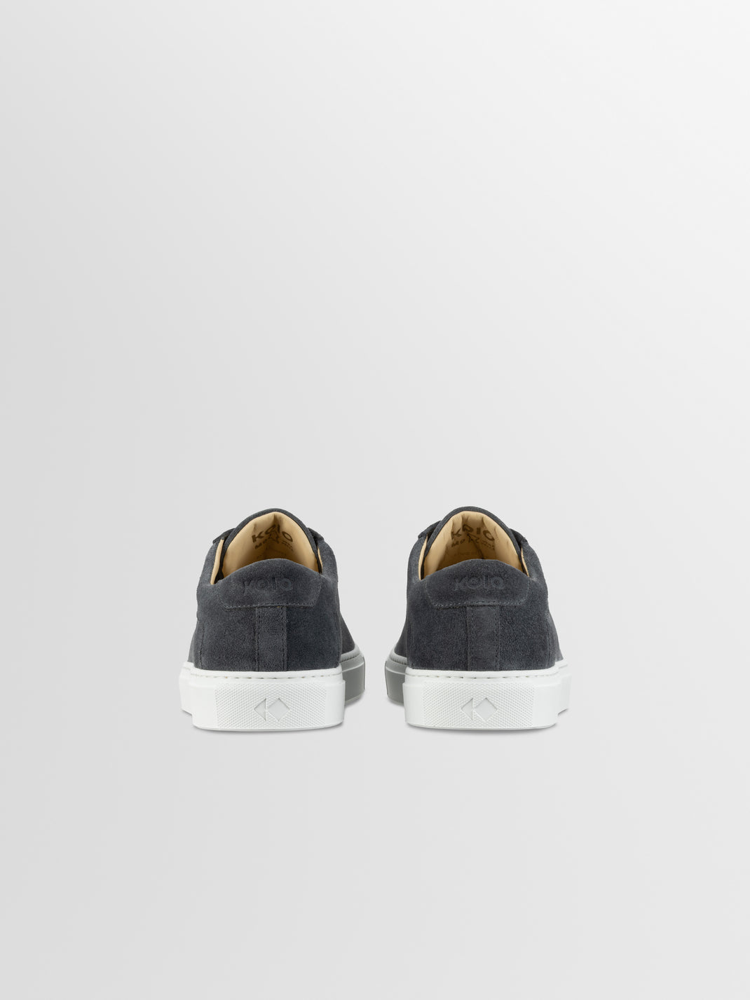 Rear view of men’s Capri in Roccia low-top sneakers showing gray suede uppers and white rubber soles on a light gray background
