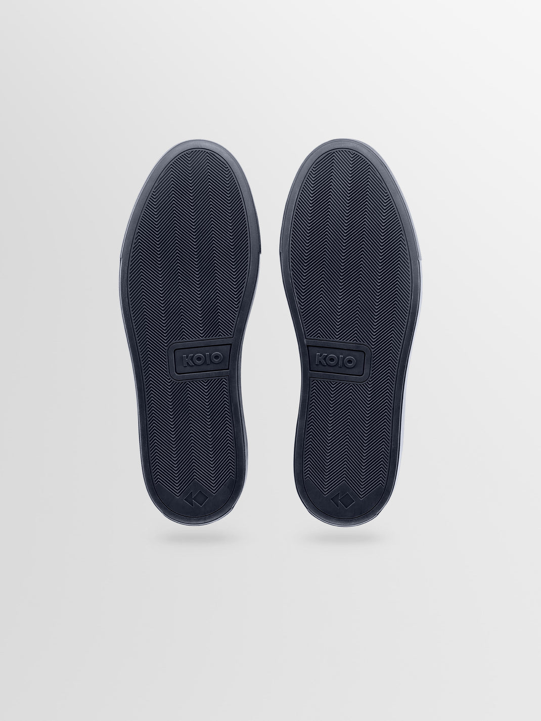 Bottom view of the men’s Capri low-top sneaker in navy leather showcasing herringbone rubber soles and KOIO branding