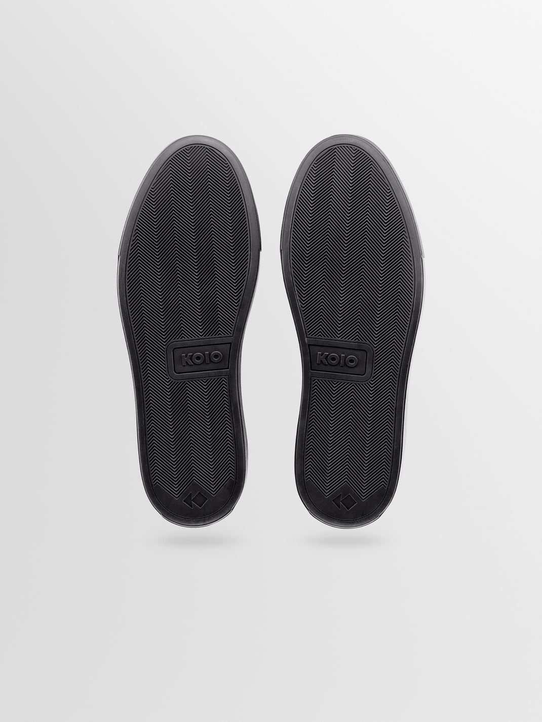 Bottom view of Capri charcoal nubuck low-top sneakers showcasing herringbone rubber soles on a light gray background