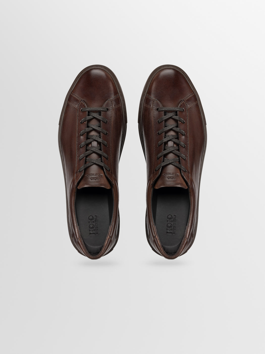Top view of men’s Capri in Antica Caffe low-top sneakers showcasing brown leather and dark laces on a light gray background