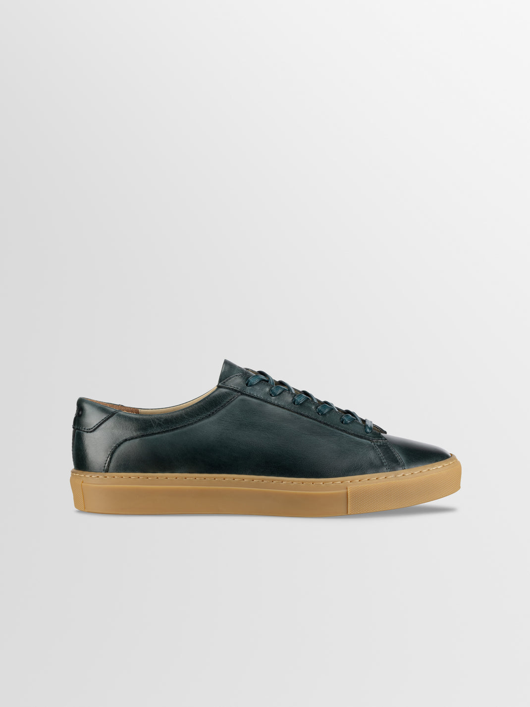 Side view of Capri in Antica Forest low-top sneaker in dark green leather with gum rubber sole on light gray background