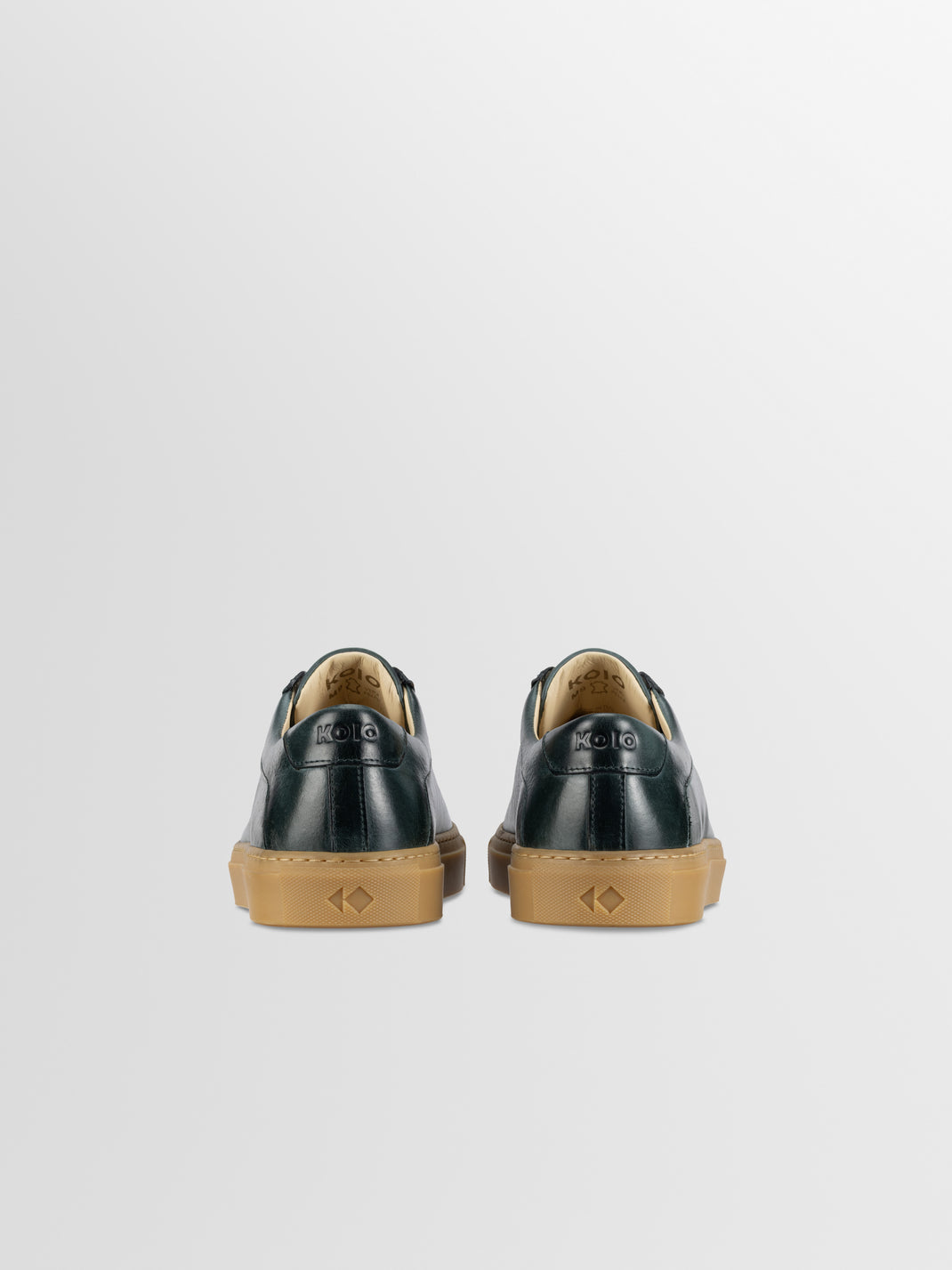 Rear view of men’s Capri in Antica Forest low-top sneakers showing dark green leather and gum rubber soles on a light gray background