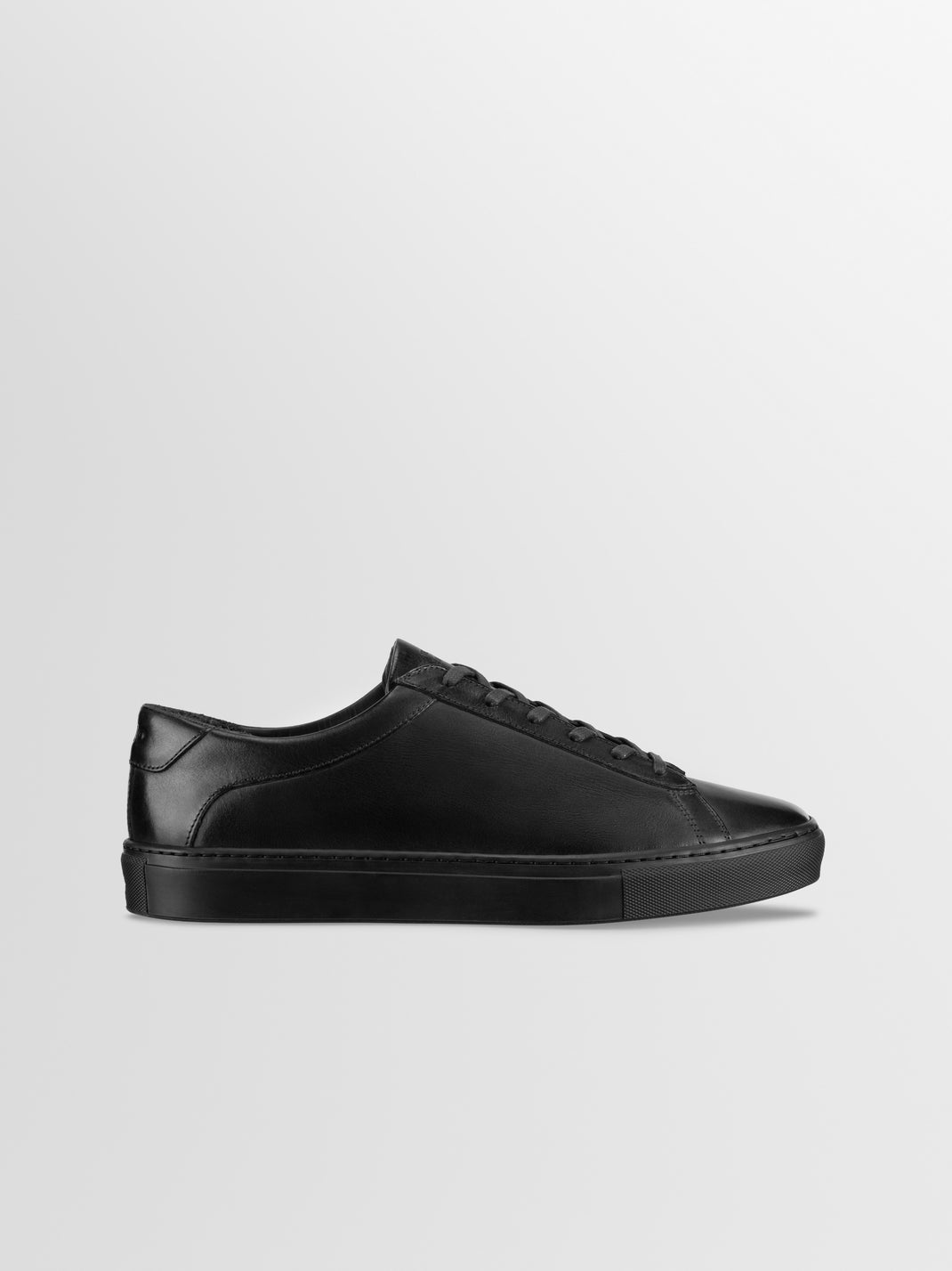 Side view of the men’s Capri in Antica Nero low-top sneaker showcasing black leather and rubber sole on a light gray background