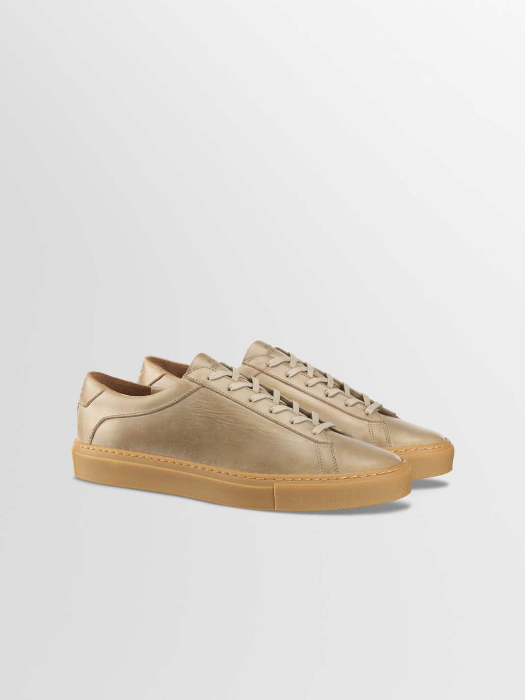 Front three-quarter view of Capri in Antica Perla men’s beige leather low-top sneakers with rubber soles on a light gray background
