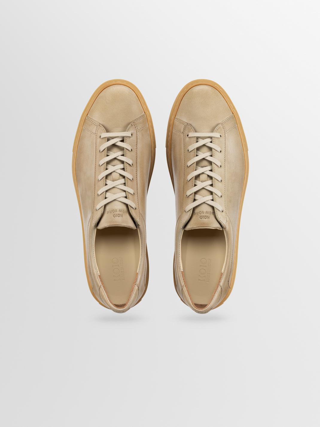 Top view of Capri in Antica Perla men’s beige leather low-top sneakers showcasing lace-up design on a light gray background