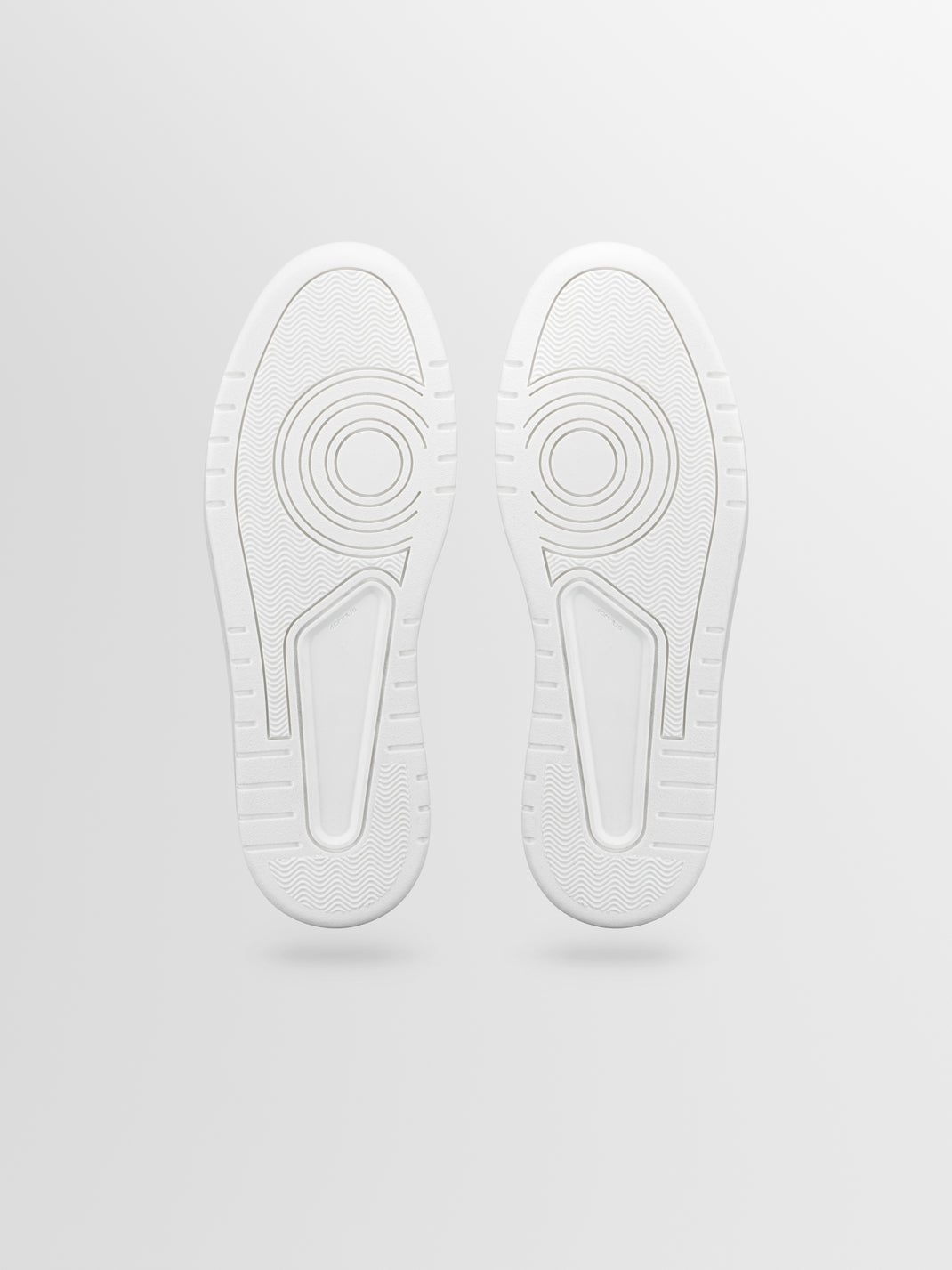 Bottom view of Carrara sneaker showcasing white rubber soles with patterned tread against a light gray background