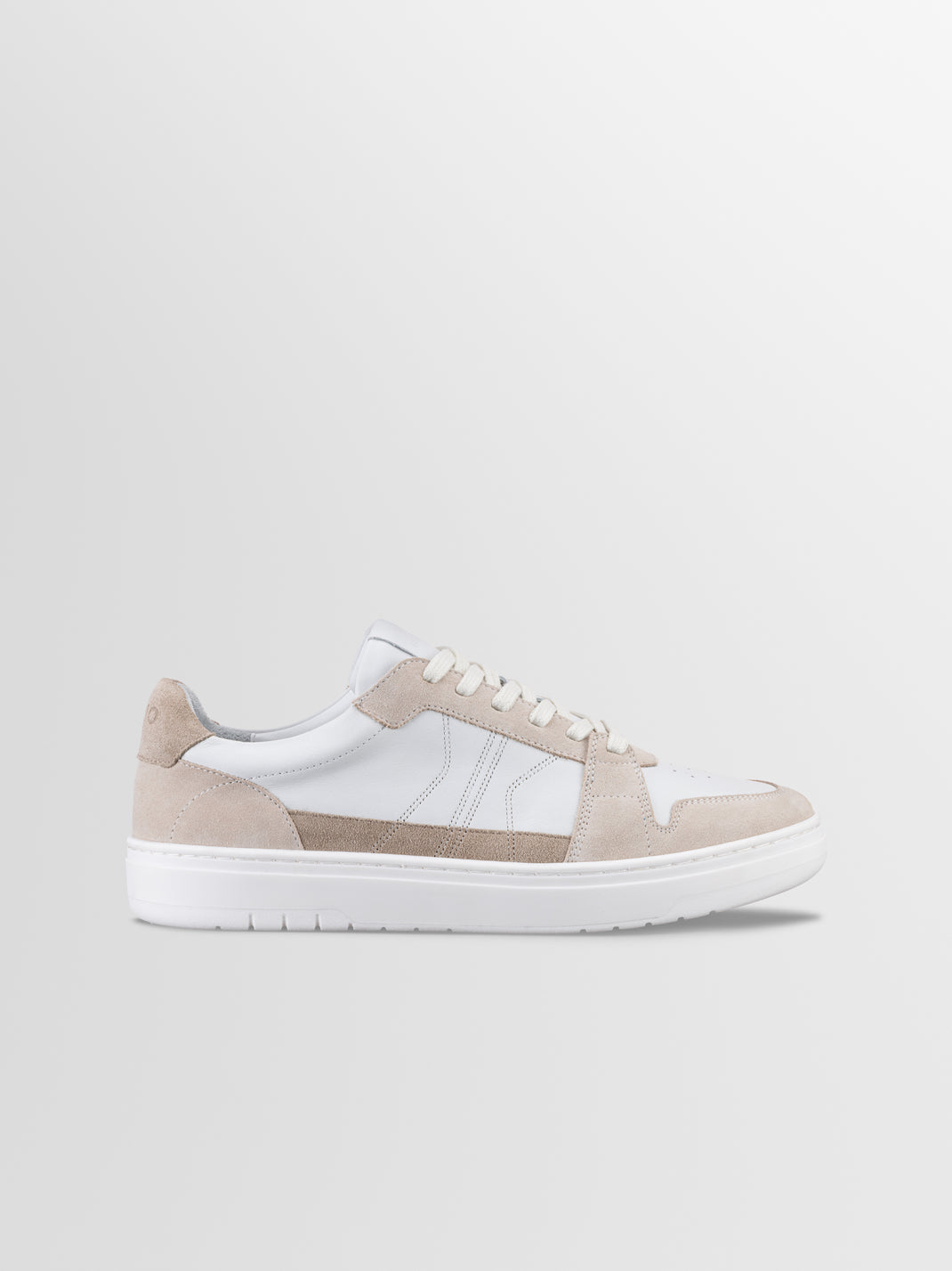 Side view of Carrara in Oyster low-top sneaker showcasing white and beige suede panels with a light gray background