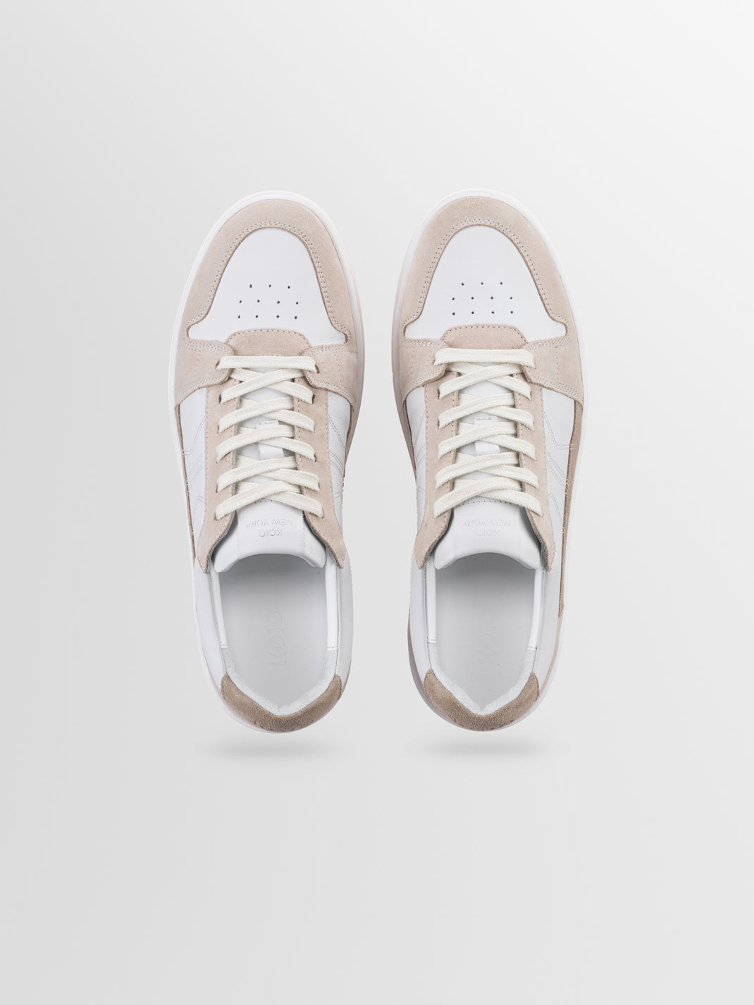 Top view of men’s Carrara in Oyster low-top sneakers showcasing white and beige suede panels on a light gray background