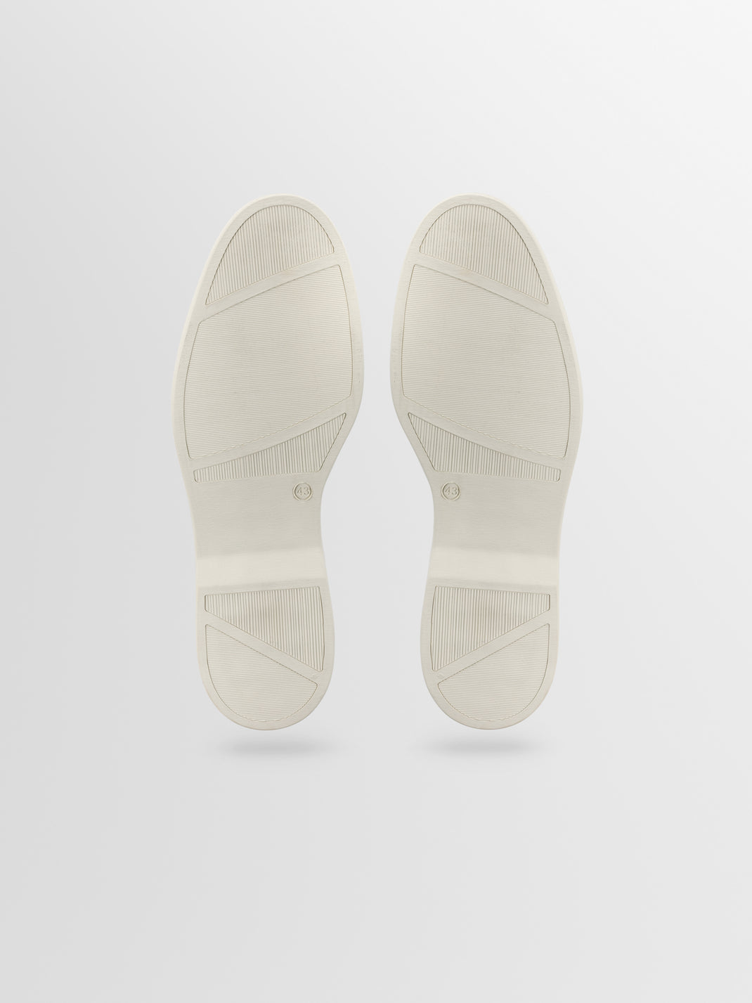 Bottom view of the Catania grey suede slip-on loafer showcasing textured rubber soles on a light gray background