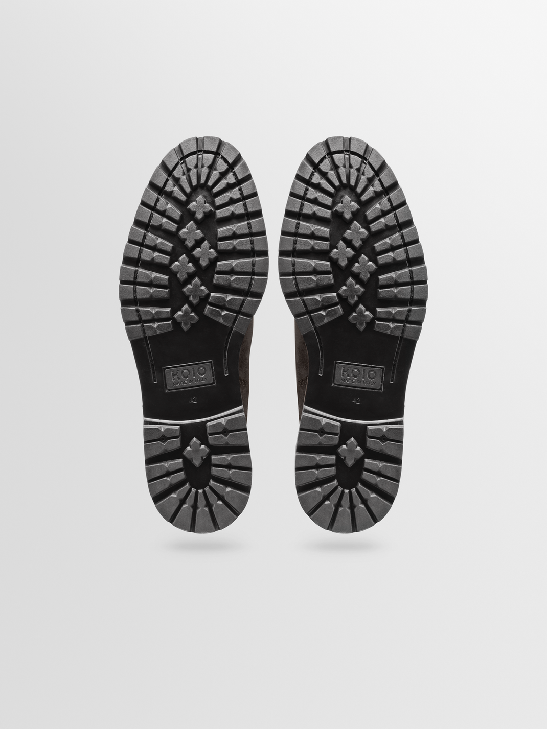 Bottom view of Fermo suede Chelsea boots in Pinecone showcasing lugged soles with a light gray background