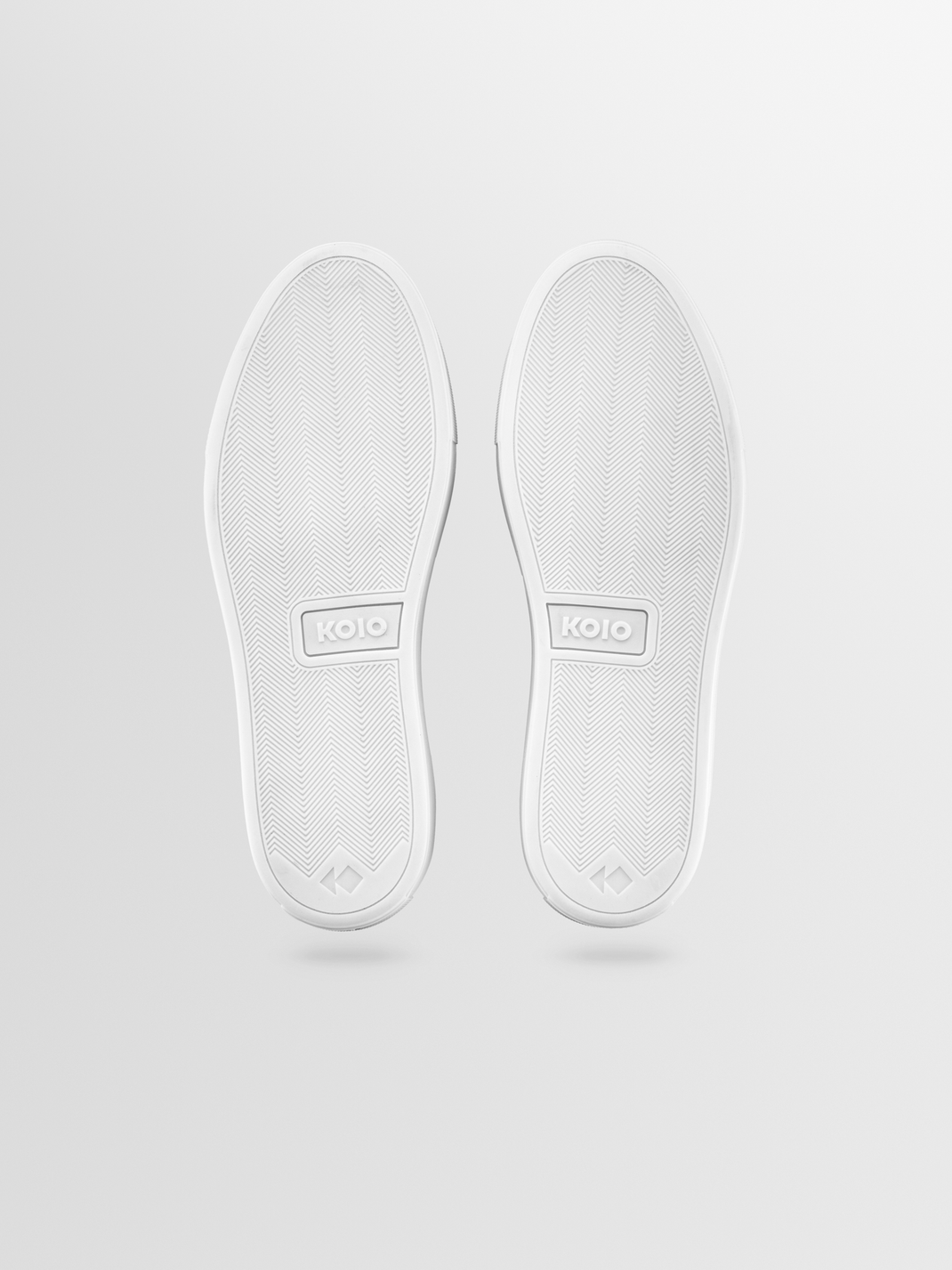 Bottom view of Garda sandstone slip-on leather sneakers showcasing white rubber soles with herringbone tread on a light gray background