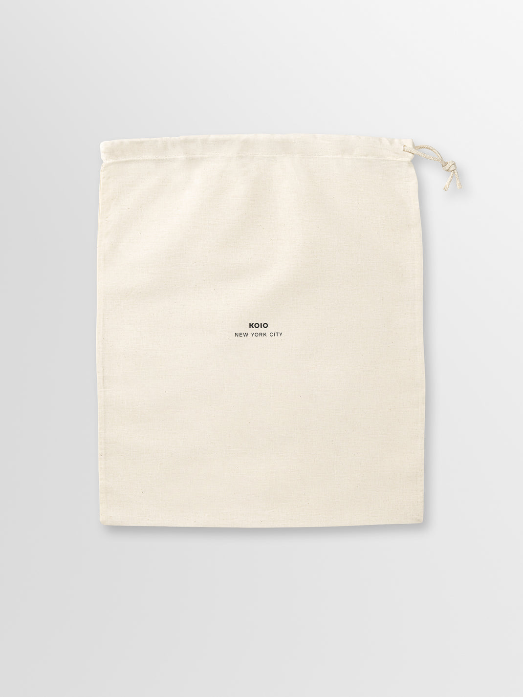 Front view of a cream drawstring dust bag showcasing the KOIO New York City logo with a light gray background