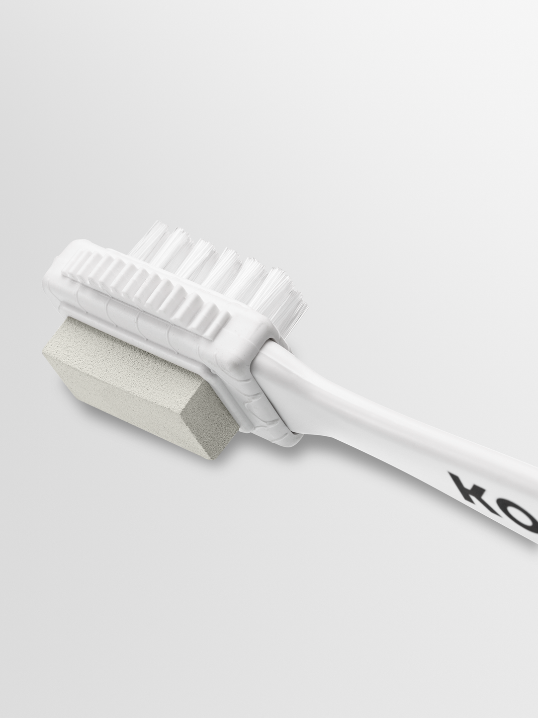 Close-up of KOIO suede brush showcasing white bristles and textured cleaning block on a light background