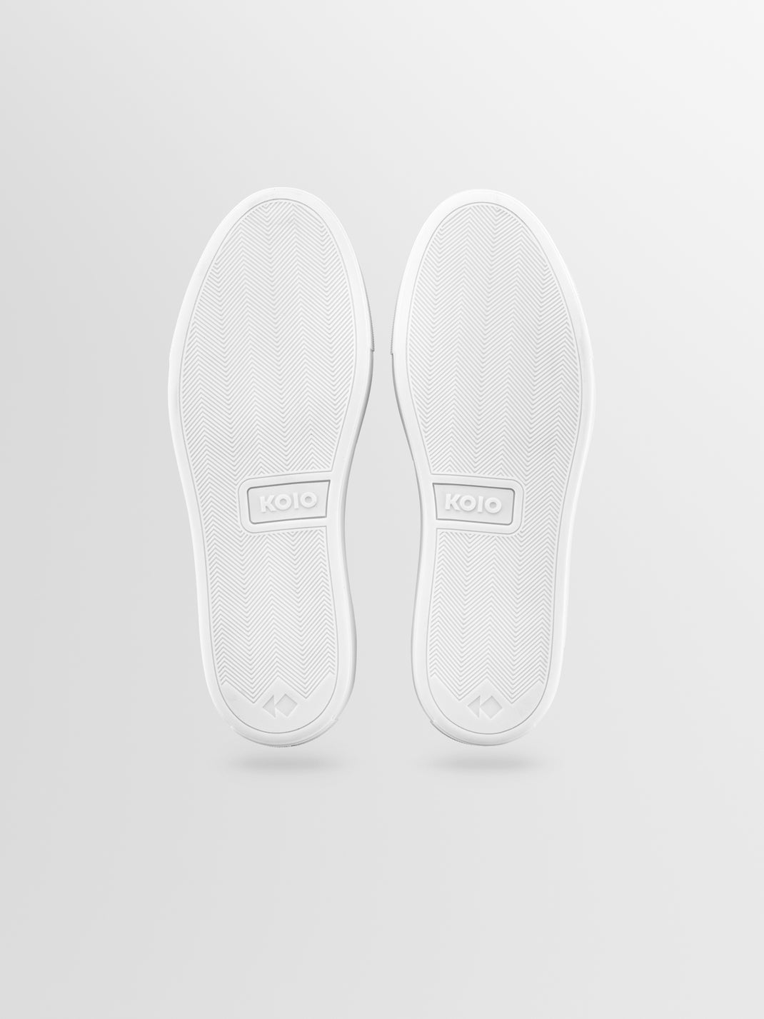 Bottom view of men’s Lido in Fawn suede slip-on loafers showcasing white rubber soles with herringbone tread on a light gray background