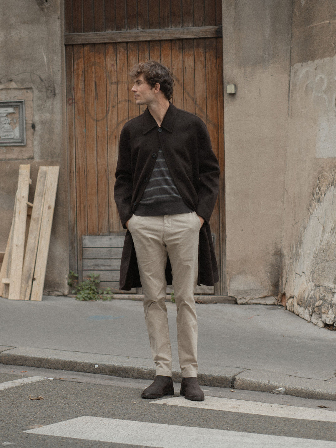 Man wearing dark brown suede Chelsea boots while standing on a city street