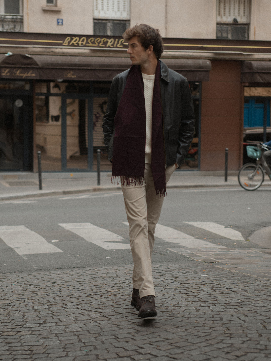 Man wearing brown suede Milo boots walks across a cobblestone street