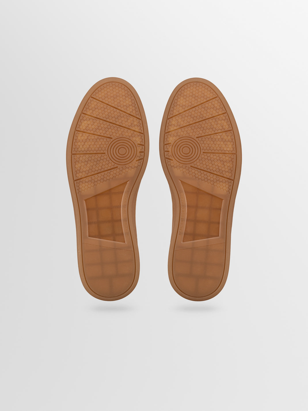 Bottom view of Monza ash gray leather low-top sneakers showcasing brown rubber soles with textured tread on a light gray background