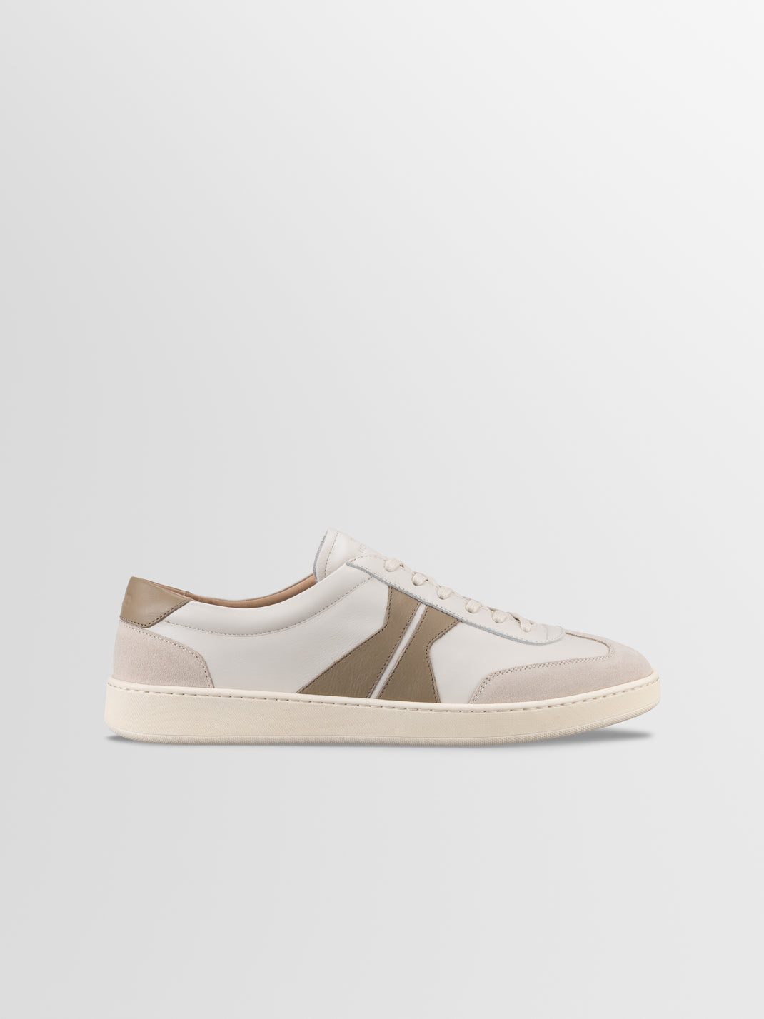 Side view of Monza low-top sneaker in latte showcasing off-white leather panels and rubber sole against a light gray background