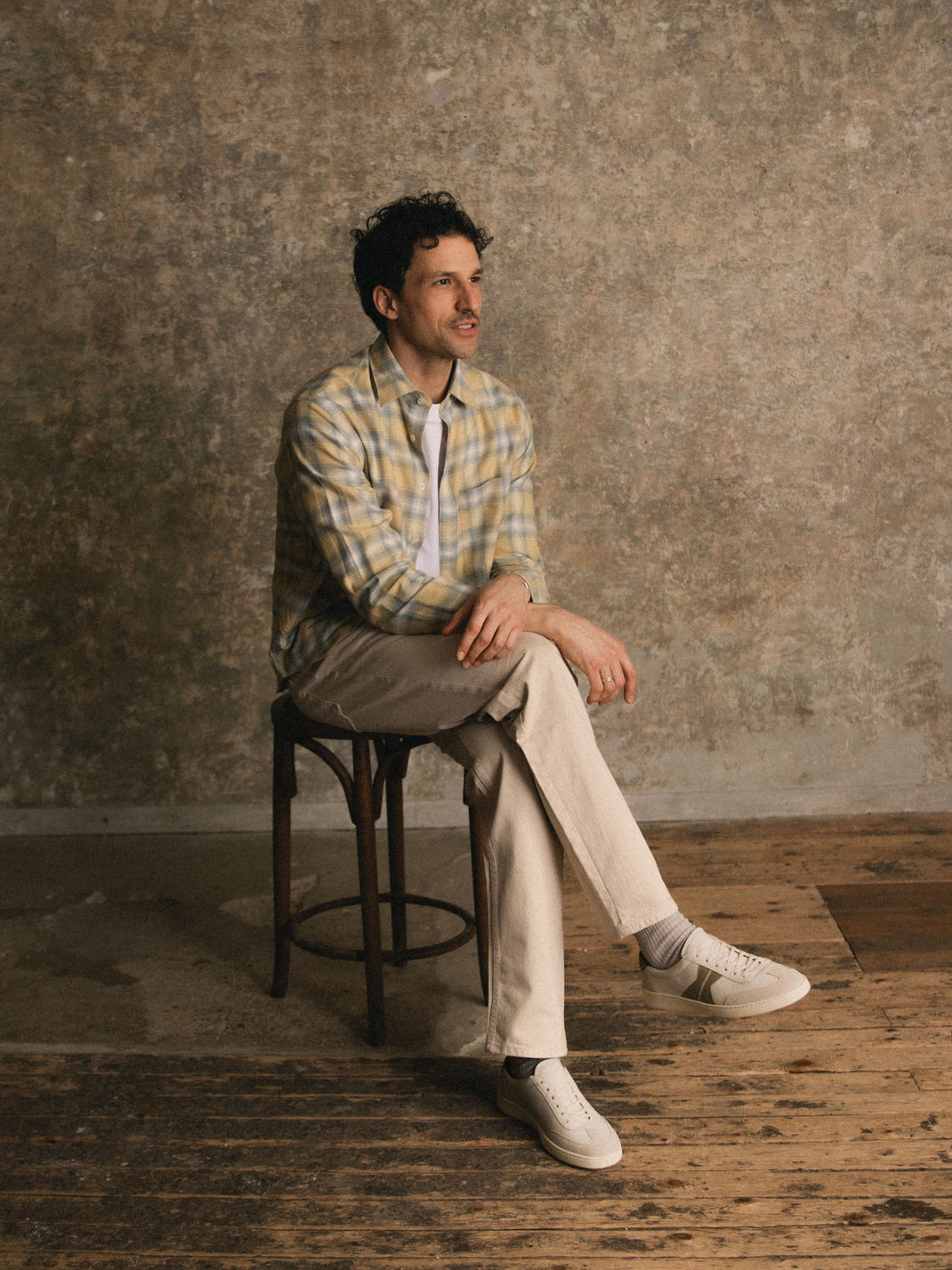 Man sitting on a stool in a studio wearing off-white leather Monza low-top sneakers