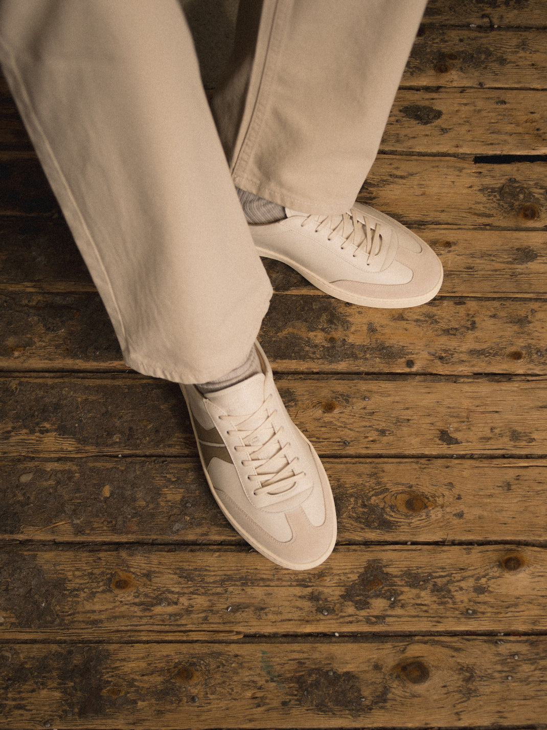 Top view of Monza in Latte men’s off-white leather low-top sneakers showcasing lace-up details with a rustic wooden floor