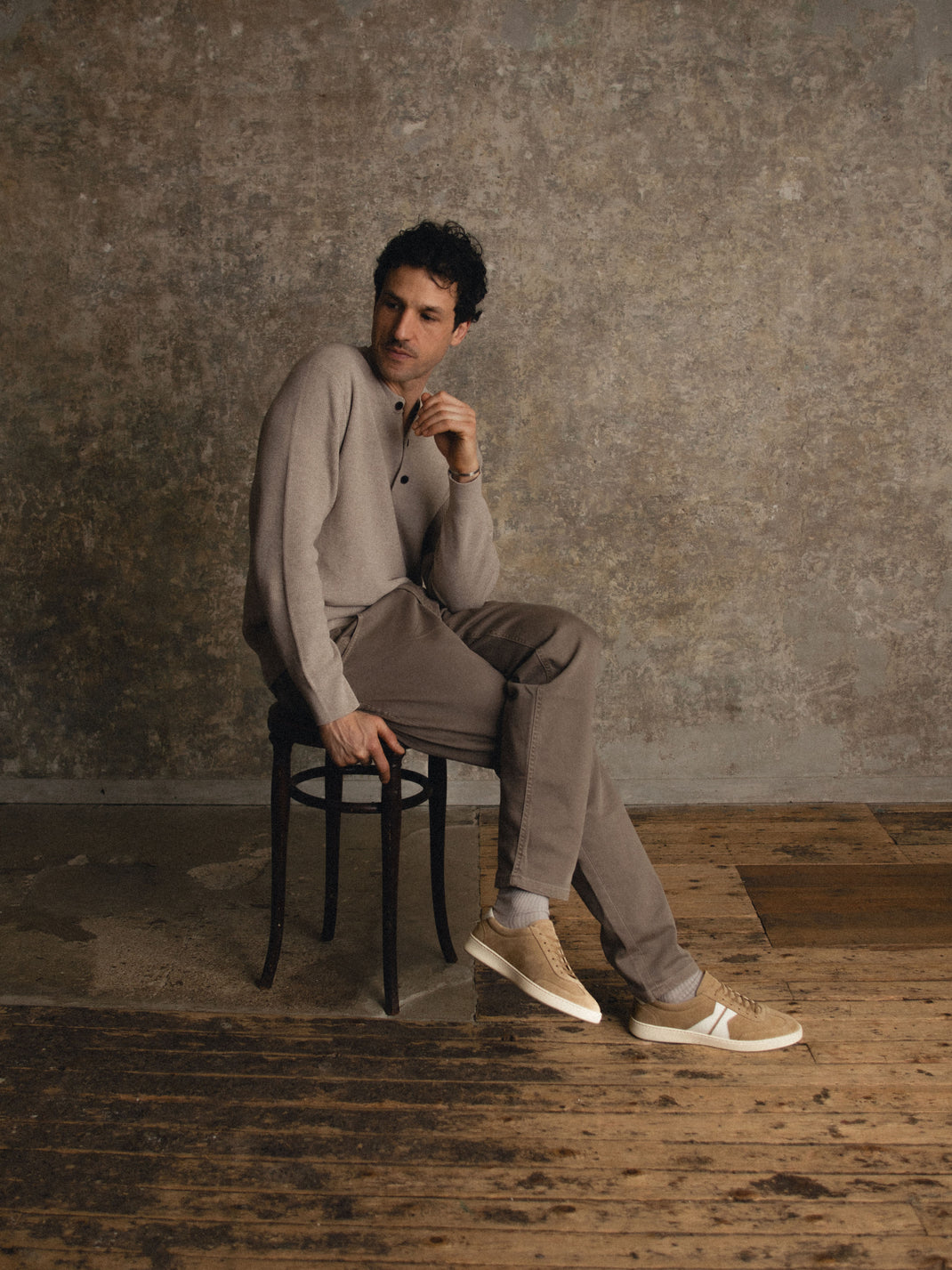 Side view of men’s Monza in Wheat low-top sneakers showcasing light brown suede and white soles with a seated model