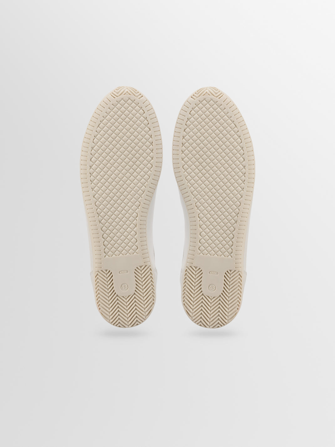 Bottom view of the Parma leather sneaker in bone showcasing textured rubber soles against a light gray background