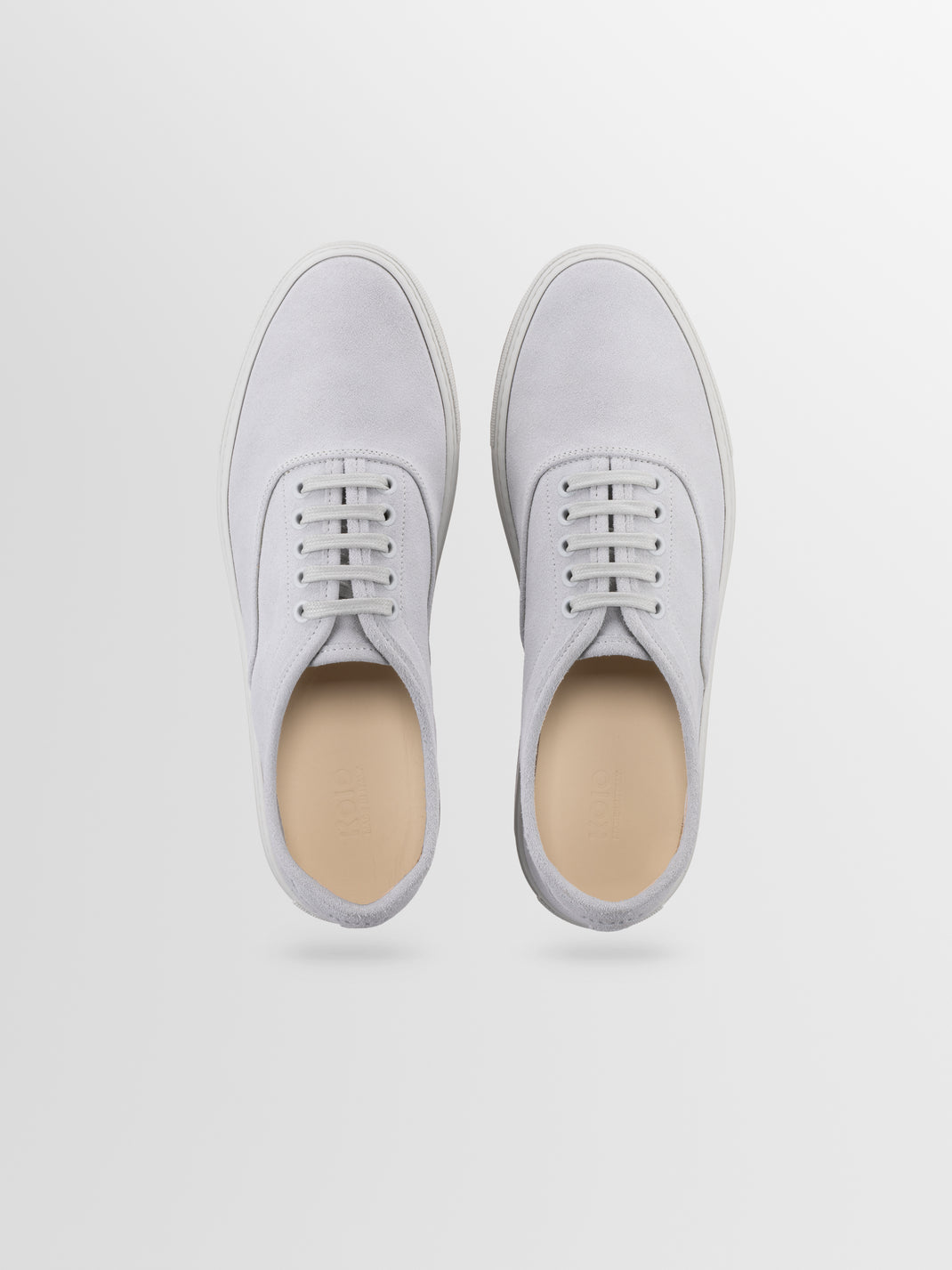 Top view of men’s white suede Portofino low-top sneakers showcasing lace-up fronts and rubber soles on a light gray background