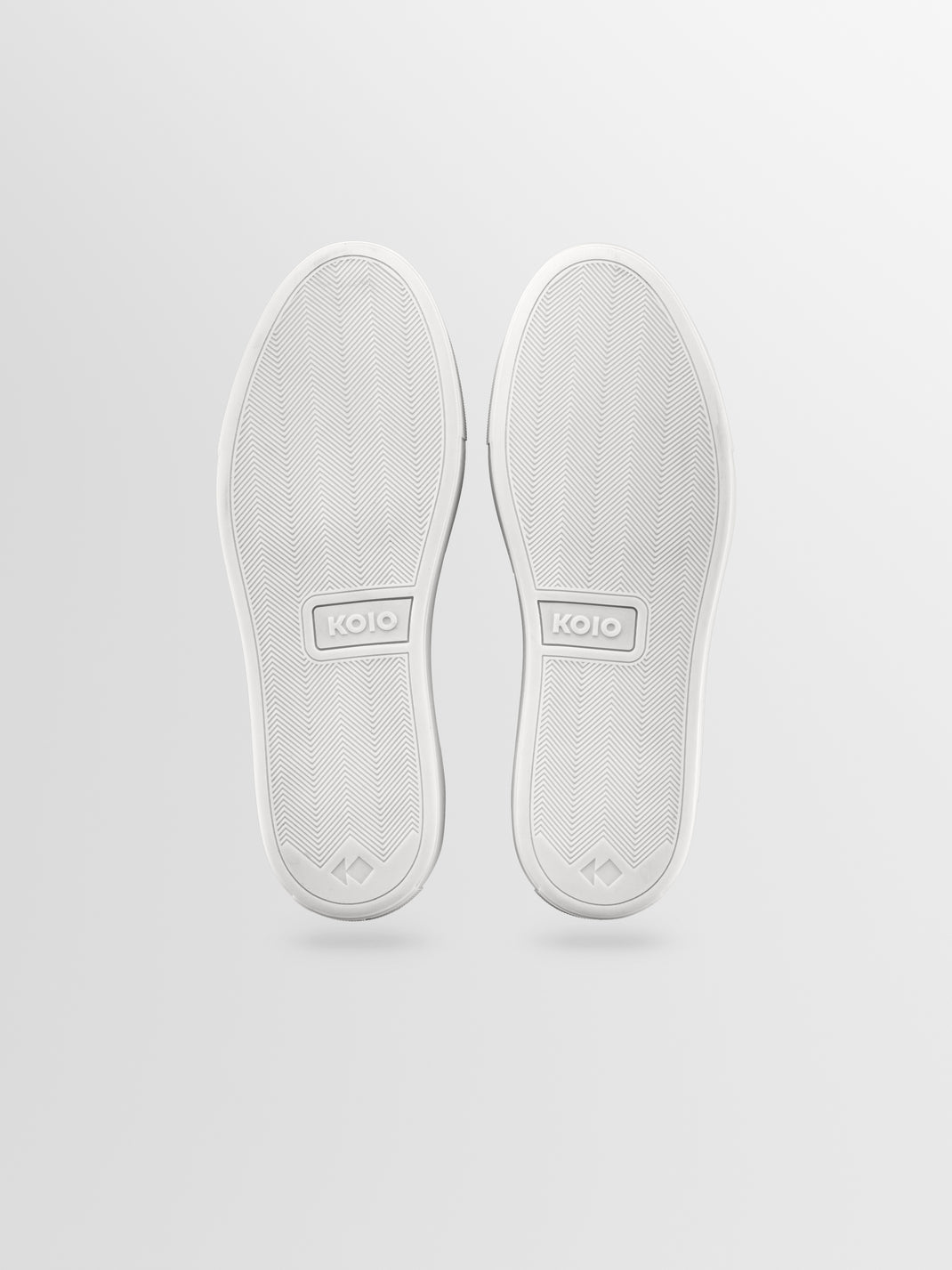 Bottom view of Portofino in Cirrus sneakers showcasing white rubber soles with herringbone tread on a light gray background